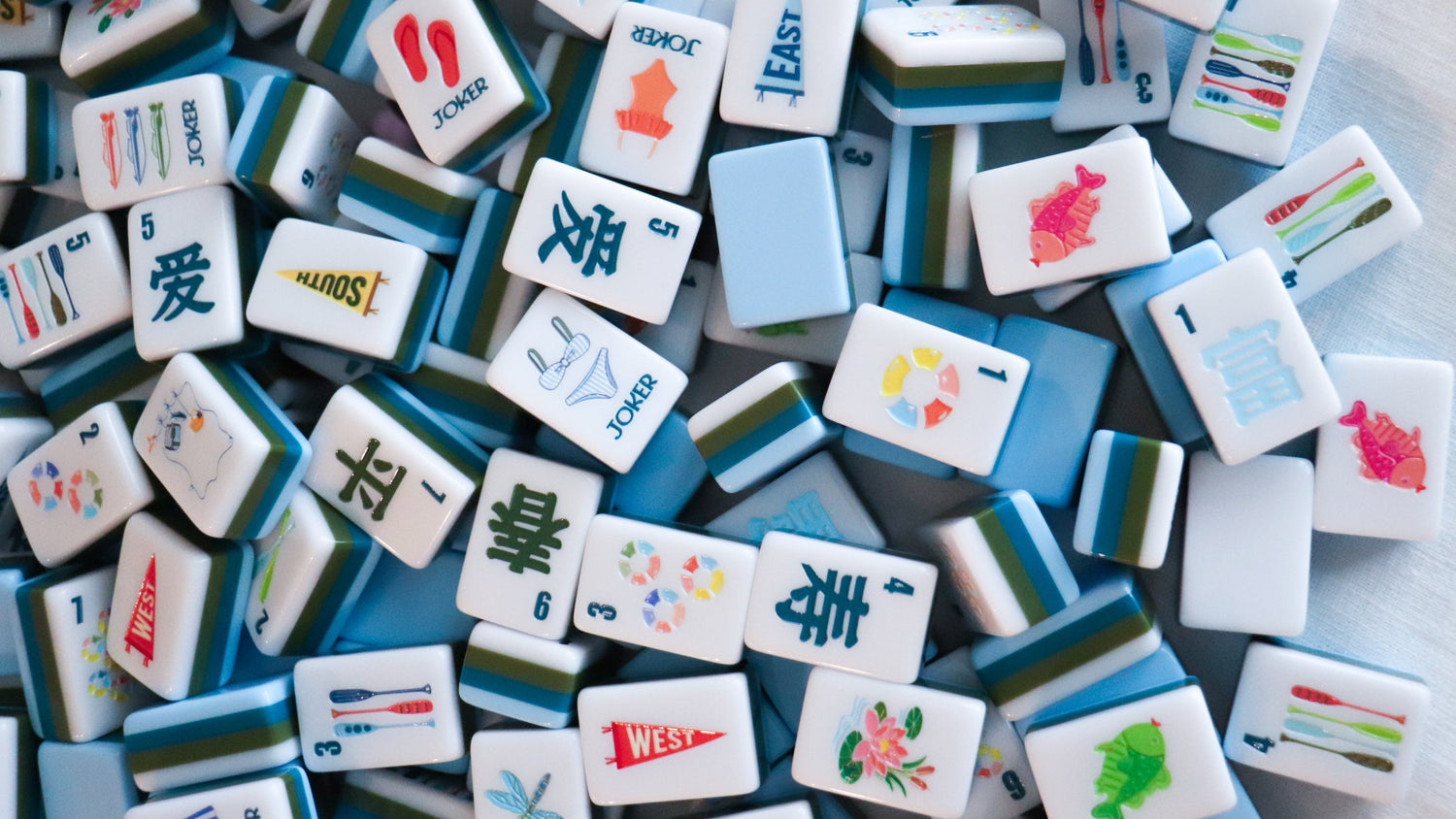 Collection of colorful Mahjong tiles on a white surface/lake inspired