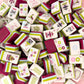 Collection of colorful game tiles with various designs on a plum and chartruse background